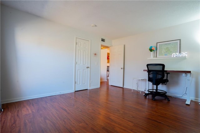 unfurnished office featuring baseboards, visible vents, and wood finished floors