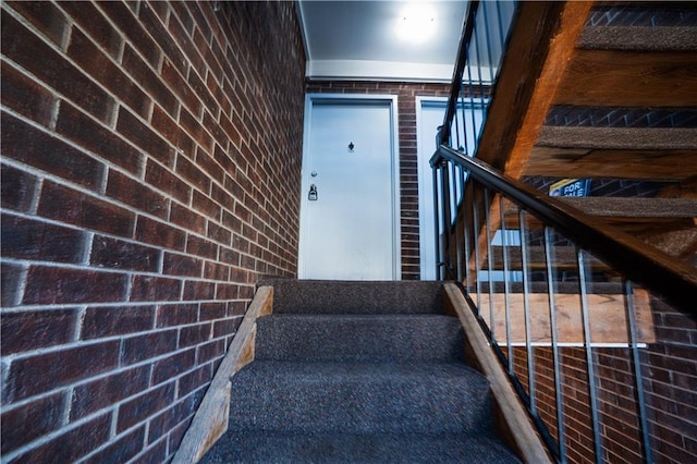 stairway featuring brick wall