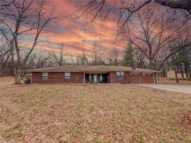 ranch-style house with an attached garage, concrete driveway, and brick siding