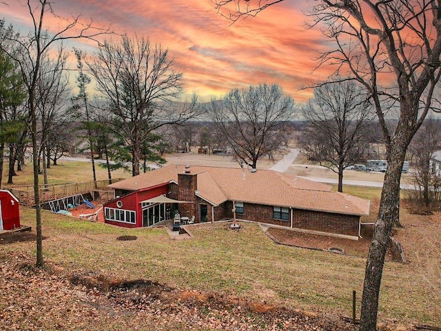 back of property featuring a chimney and a lawn