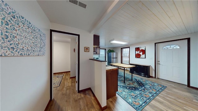 foyer entrance with visible vents, beamed ceiling, baseboards, and light wood-style floors