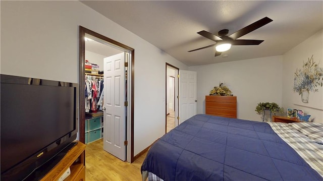 bedroom featuring a spacious closet, a ceiling fan, light wood-type flooring, and a closet