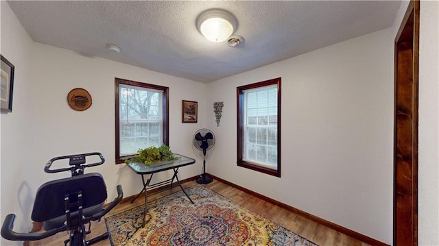 office area with visible vents, a textured ceiling, baseboards, and wood finished floors