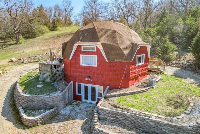 view of property exterior featuring central air condition unit, a wooden deck, french doors, and roof with shingles