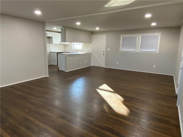 unfurnished living room featuring dark wood-type flooring, a sink, and recessed lighting