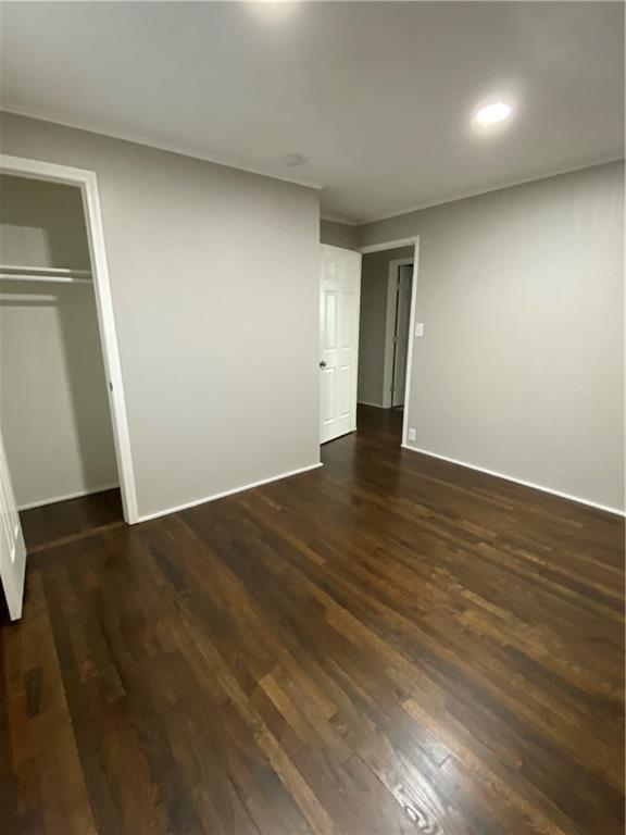 unfurnished bedroom featuring dark wood finished floors and a closet