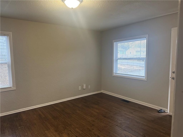 empty room with dark wood-style floors, baseboards, and a textured ceiling