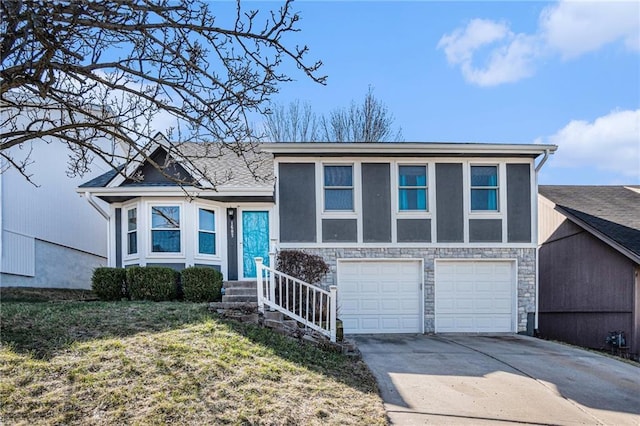 split level home with concrete driveway, an attached garage, stone siding, and stucco siding