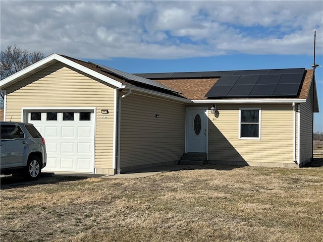 ranch-style home featuring entry steps, solar panels, a front lawn, and a garage