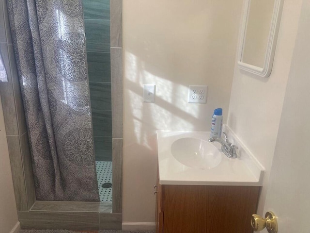 bathroom with tiled shower and vanity