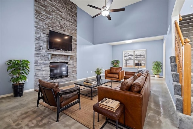 living room featuring baseboards, a towering ceiling, stairway, concrete flooring, and a fireplace