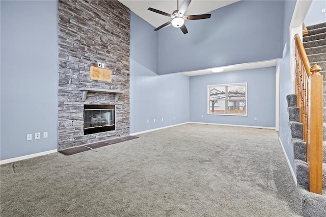 unfurnished living room with carpet flooring, a fireplace, a high ceiling, and stairs