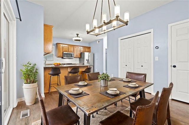 dining area featuring visible vents, an inviting chandelier, and wood finished floors