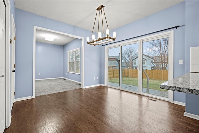 unfurnished dining area featuring visible vents, baseboards, a chandelier, and dark wood-type flooring