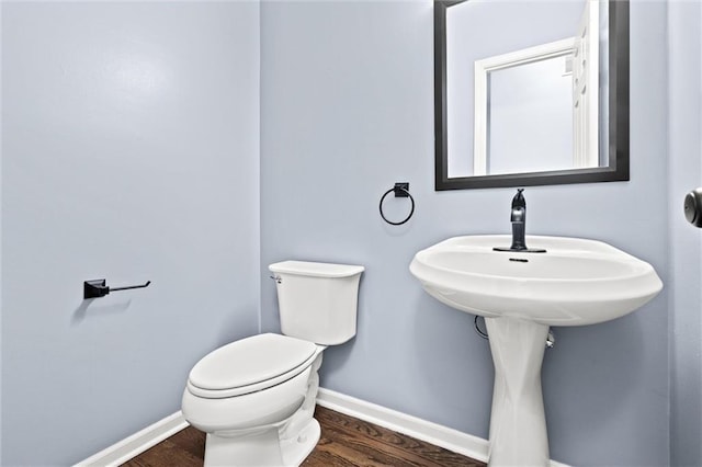 bathroom with wood finished floors, toilet, and baseboards