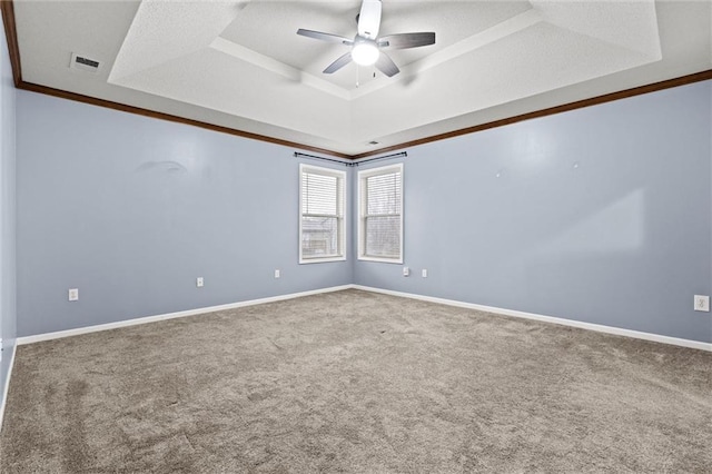 carpeted spare room featuring a tray ceiling, visible vents, ceiling fan, and baseboards