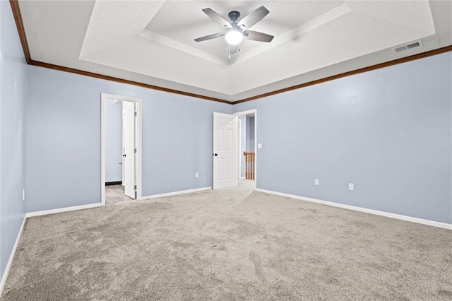 unfurnished room featuring visible vents, a raised ceiling, a ceiling fan, baseboards, and carpet