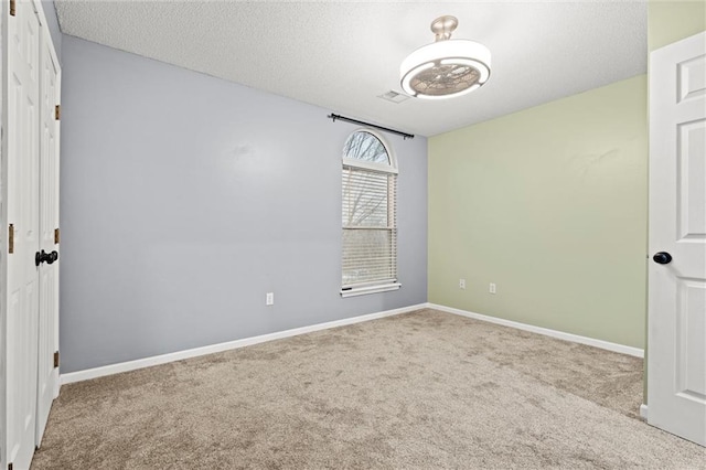 spare room with visible vents, a textured ceiling, baseboards, and carpet flooring