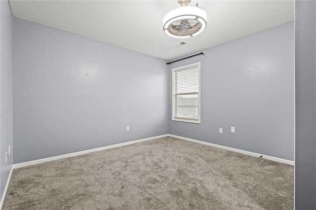 empty room with visible vents, a textured ceiling, baseboards, and carpet flooring