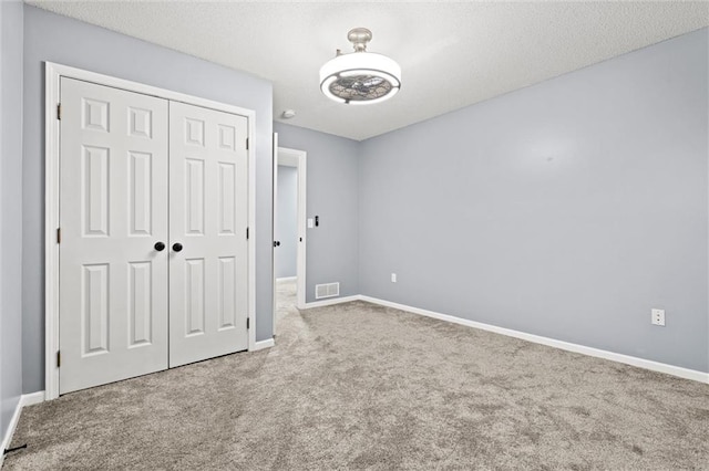 unfurnished bedroom with baseboards, a closet, visible vents, and carpet flooring