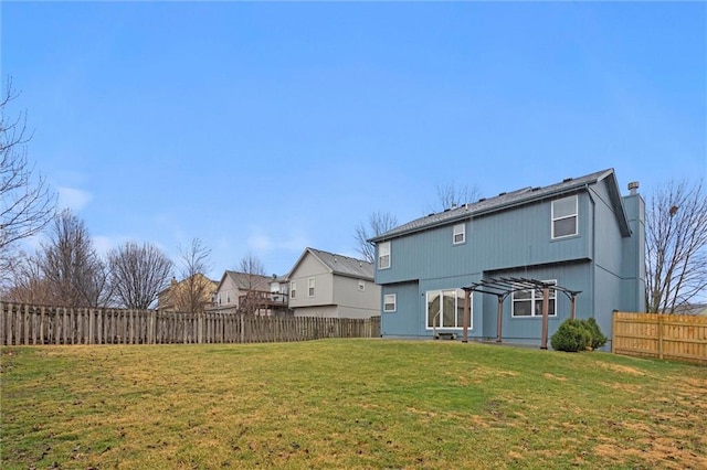 rear view of house featuring a yard and a fenced backyard