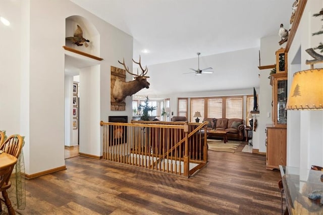 interior space with a fireplace, ceiling fan, vaulted ceiling, wood finished floors, and baseboards