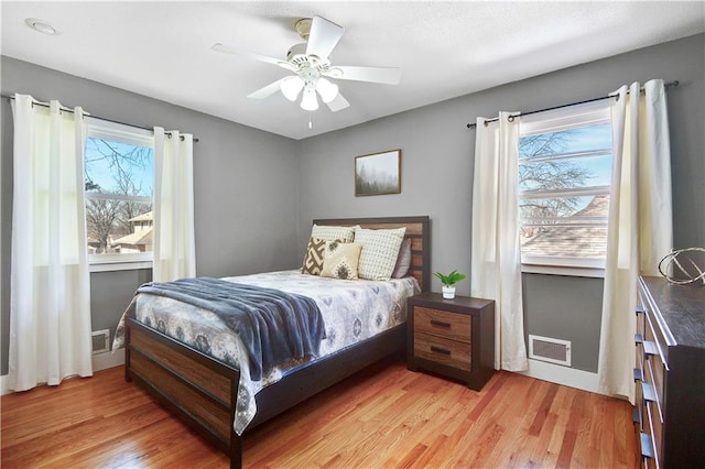 bedroom featuring a ceiling fan, multiple windows, light wood-style floors, and visible vents