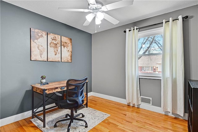 office area with visible vents, light wood-style flooring, baseboards, and ceiling fan