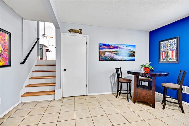 dining room featuring stairway, a ceiling fan, baseboards, light tile patterned flooring, and a textured ceiling