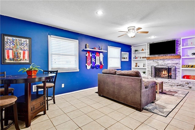 living area with a large fireplace, built in features, light tile patterned floors, and a textured ceiling