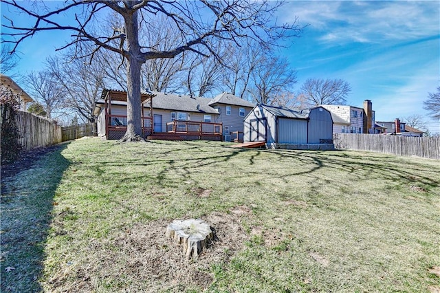 view of yard featuring an outbuilding, a wooden deck, a storage unit, and a fenced backyard