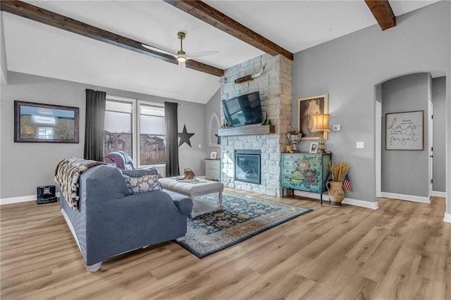 living area with lofted ceiling with beams, a fireplace, baseboards, and wood finished floors