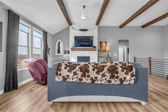 living room featuring light wood-type flooring, plenty of natural light, a fireplace, and lofted ceiling with beams