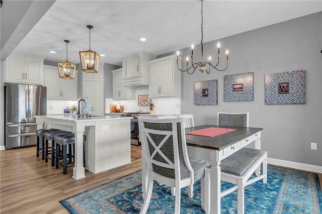 dining space featuring an inviting chandelier, recessed lighting, light wood-style flooring, and baseboards