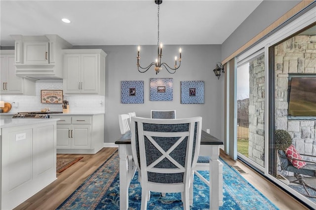 dining room featuring light wood-style flooring, visible vents, a chandelier, and baseboards