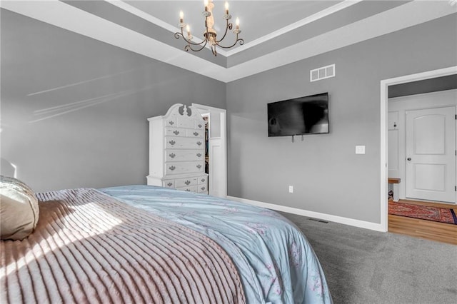 bedroom featuring carpet floors, a tray ceiling, a notable chandelier, visible vents, and baseboards