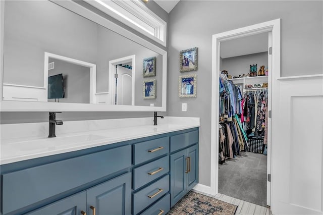 full bathroom featuring double vanity, a spacious closet, and a sink