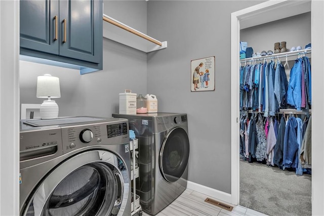 washroom featuring washer and dryer, cabinet space, visible vents, and baseboards