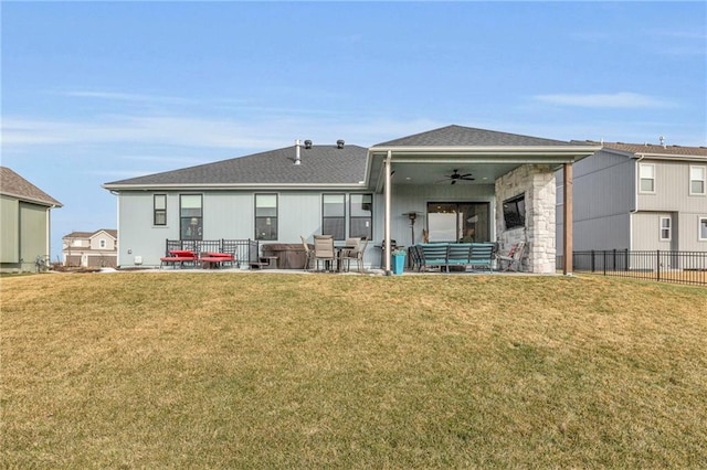 back of property with a shingled roof, a ceiling fan, a lawn, fence, and a patio area