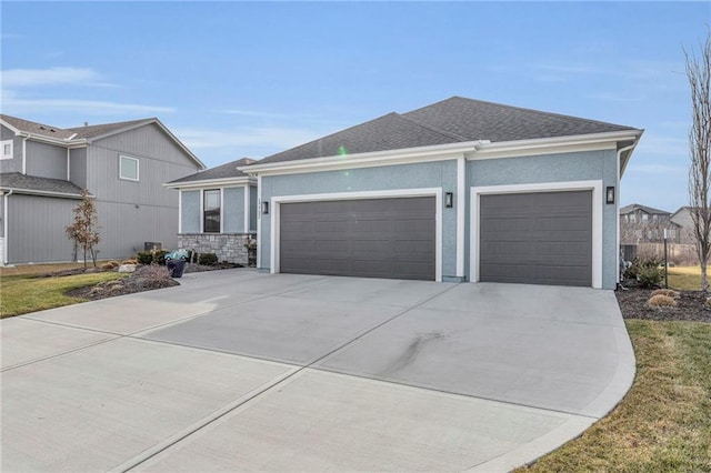 view of front of property with an attached garage, roof with shingles, concrete driveway, and stucco siding