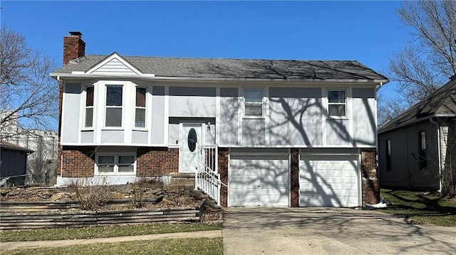 raised ranch featuring stucco siding, driveway, an attached garage, brick siding, and a chimney