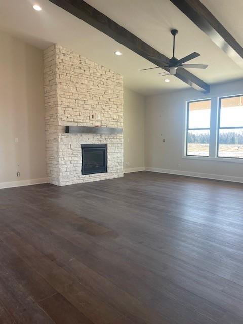 unfurnished living room featuring dark wood-style floors, ceiling fan, a fireplace, and baseboards