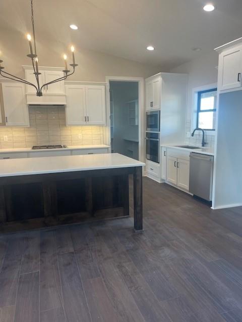 kitchen with lofted ceiling, light countertops, stainless steel dishwasher, white cabinetry, and gas cooktop