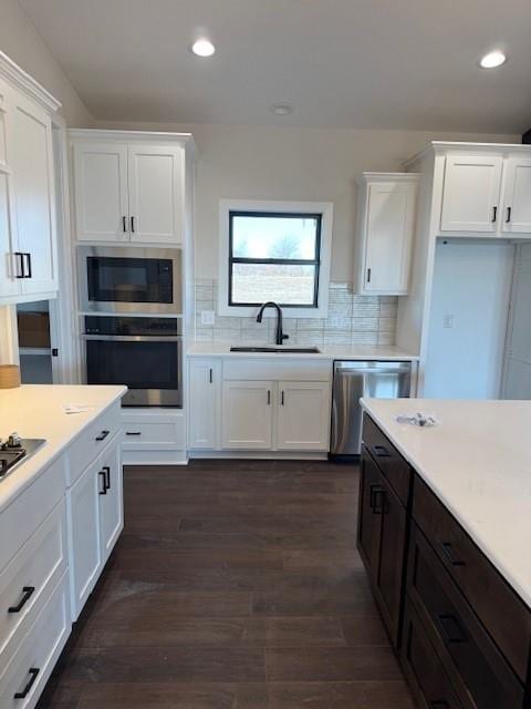 kitchen featuring appliances with stainless steel finishes, white cabinetry, and a sink