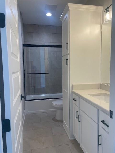 bathroom with recessed lighting, toilet, combined bath / shower with glass door, vanity, and tile patterned flooring