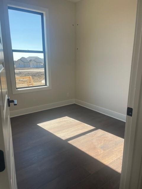 spare room with dark wood finished floors and baseboards