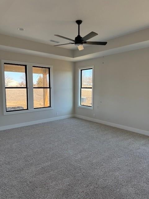 spare room featuring carpet, a raised ceiling, ceiling fan, and baseboards