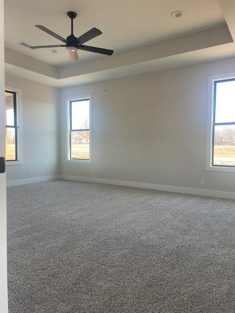 unfurnished room with carpet floors, ceiling fan, baseboards, and a raised ceiling