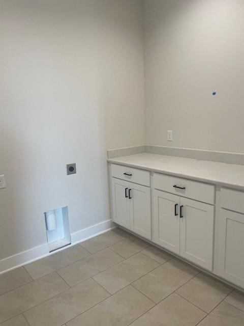 laundry area featuring cabinet space, electric dryer hookup, baseboards, and light tile patterned floors