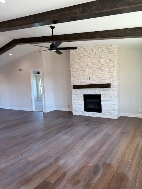 unfurnished living room with dark wood-style floors, ceiling fan, a stone fireplace, and baseboards